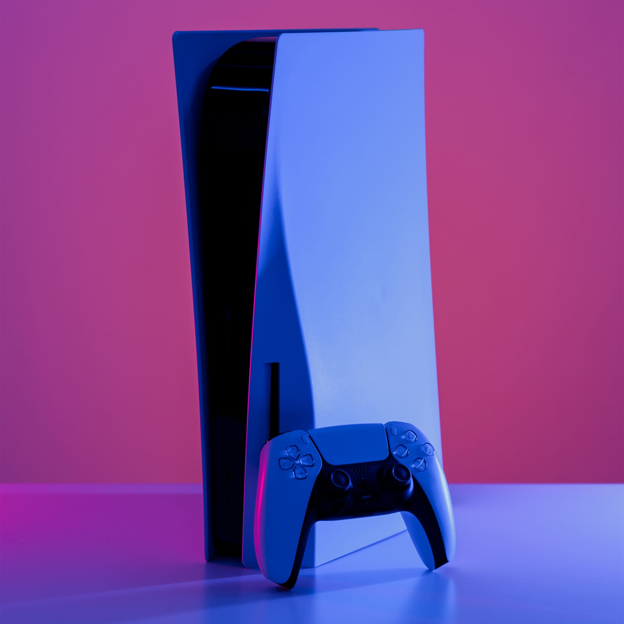 PS5 DualSense wireless controller resting upright against the standard edition PS5 console.