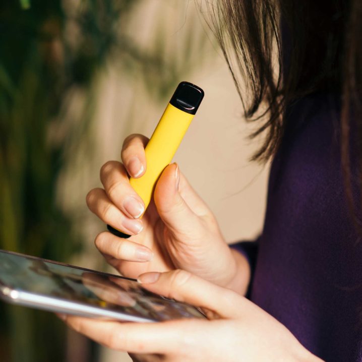 woman holding a yellow disposable vape