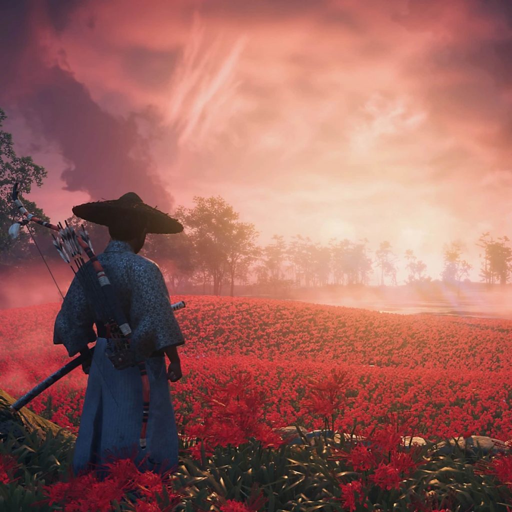 Jin Sakai standing in front of a red flower field in Ghost of Tsushima: Director's Cut.