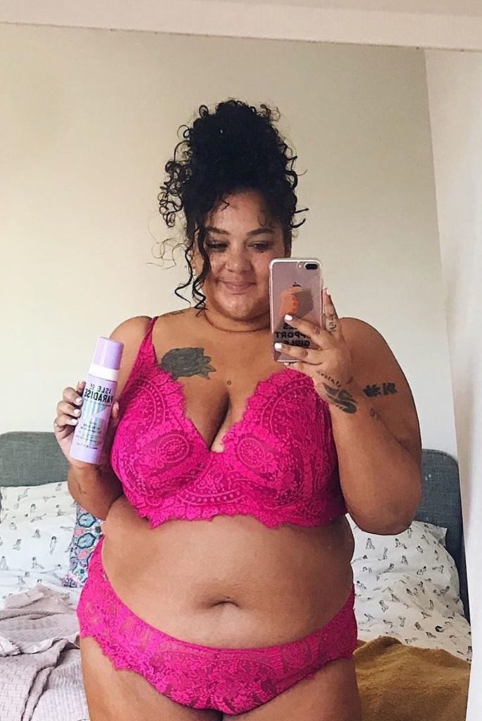 Body positive activist and television presenter Grace F Victory poses in pink lacy lingerie holding bottle of Isle of Paradise.Image credit: Instagram @theisleofparadise