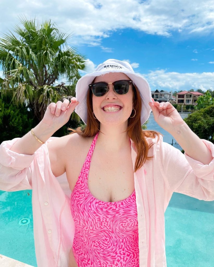Courtney Mangan, four time cancer survivor, poses poolside and sun safe, in a protective shirt and hat. 