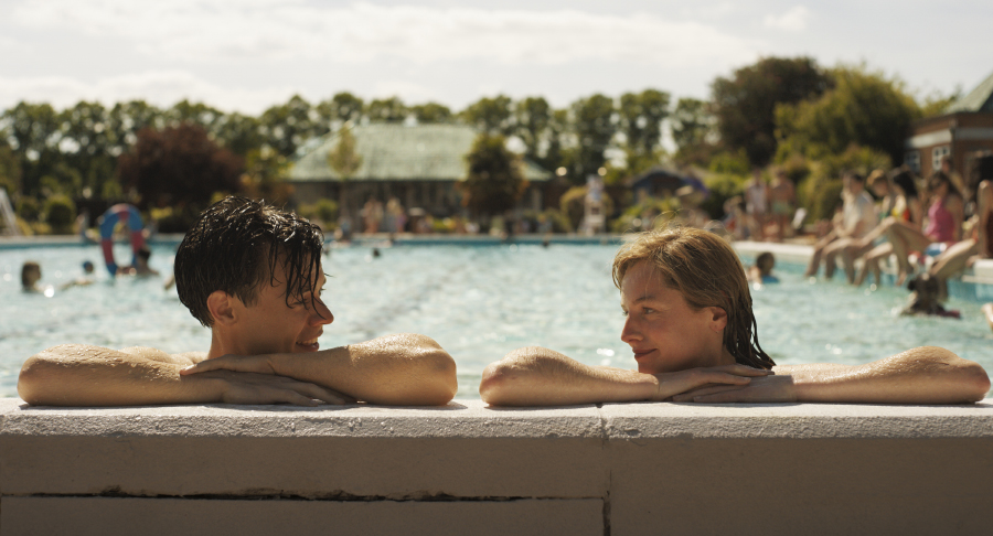 Harry Styles and Emma Corrin lean against the edge of the swimming pool in My Policeman.