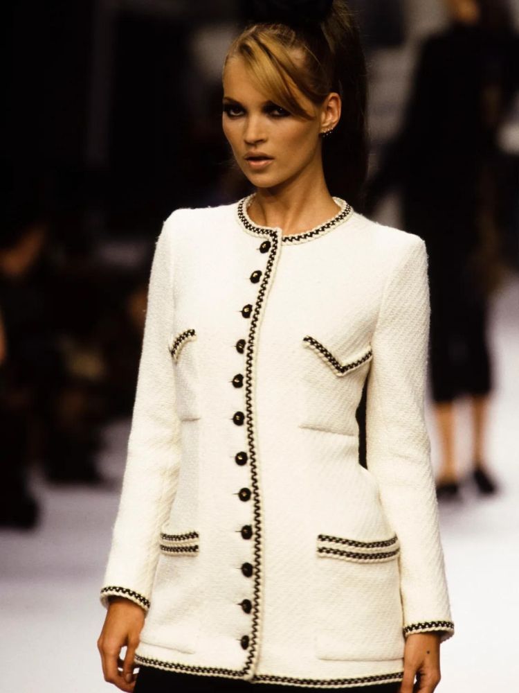 Kate Moss in a white tweed coat, charcoal smokey eye with triple ear piercing at on the Chanel, couture spring/summer 1995 