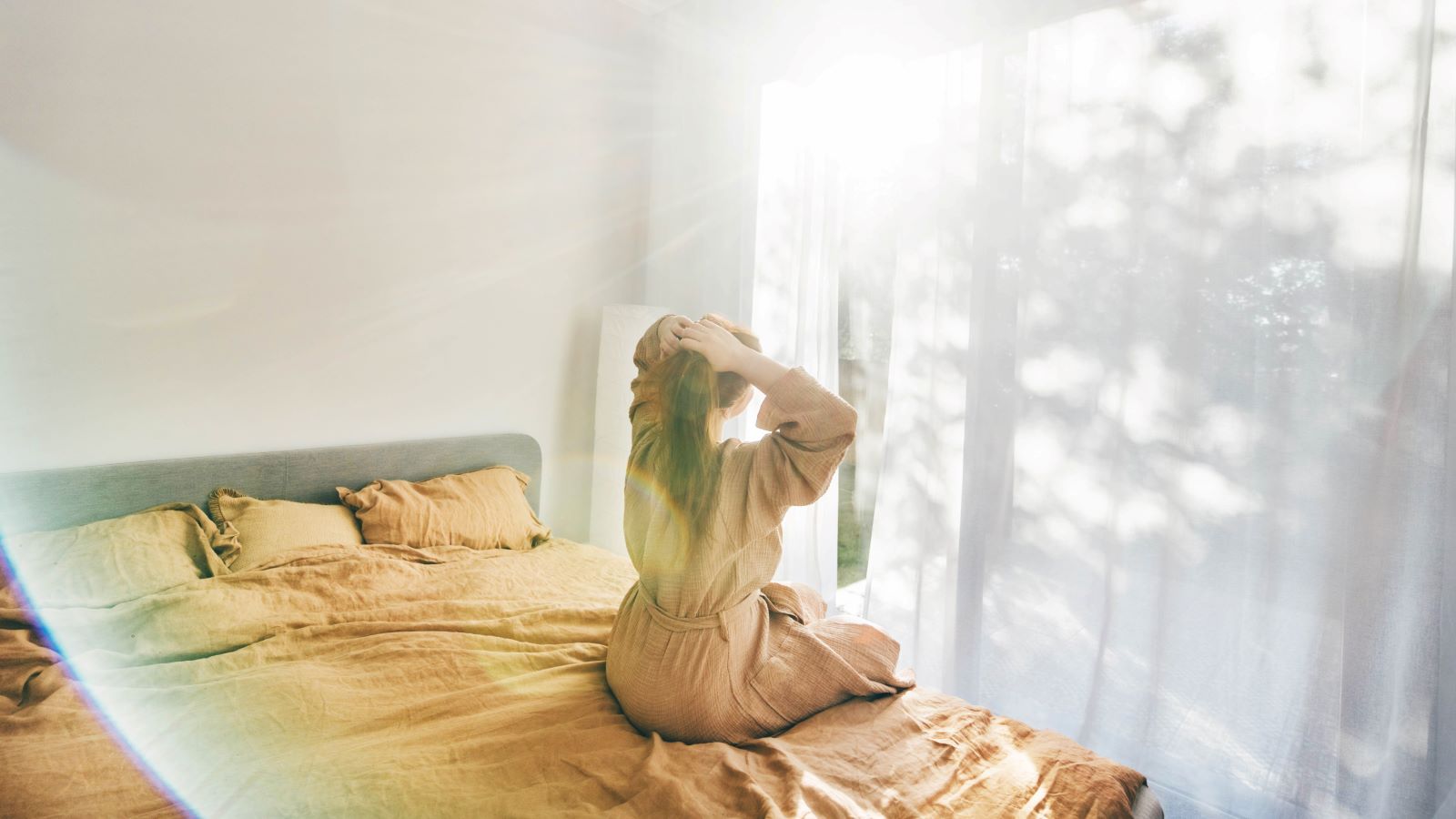 woman soaking in sunlight on bed