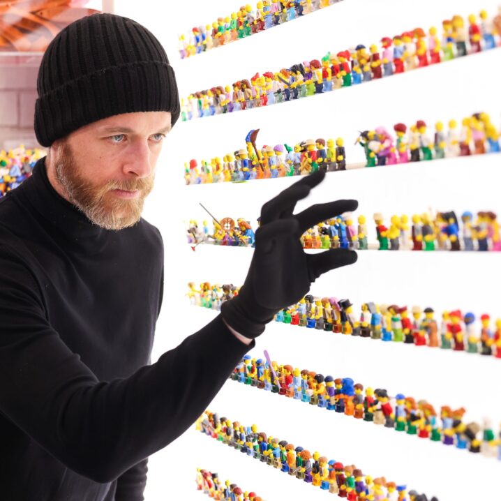 Hamish Blake in a Heist Costume picking up a LEGO minifig - When is Lego Masters Finale 2023