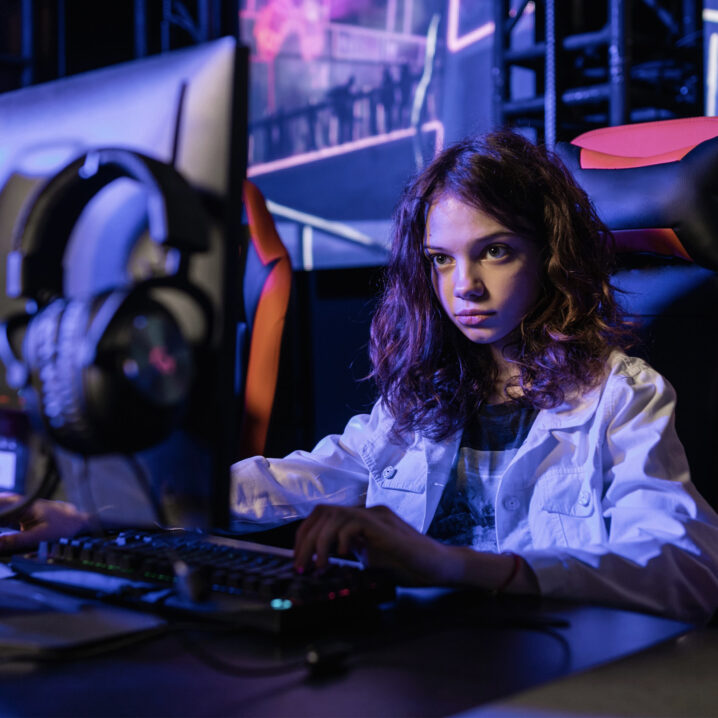 Girl sitting at desk playing video games on desktop computer